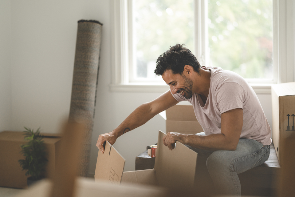 A mature hispanic man is packing and unpacking as he is moving into a new house.