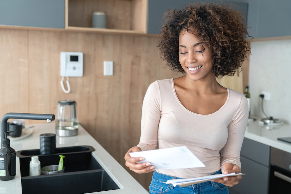 Portrait of an African American woman at home checking her mail and looking very happy – lifestyle concepts
