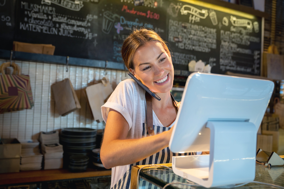 Waitress talking on the phone at a restaurant taking a delivery order and looking happy - food service concepts